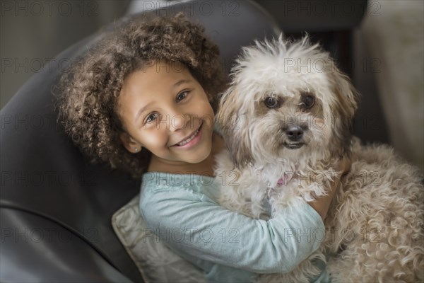 Mixed race girl petting dog on sofa