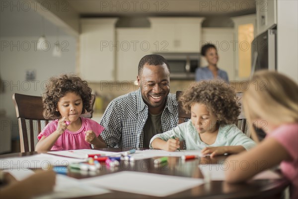 Father and children drawing in kitchen