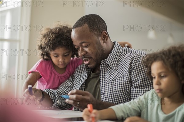 Father and daughters drawing at table