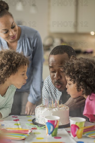 Father blowing birthday candles at party