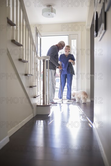 Nurse helping patient walk with cane