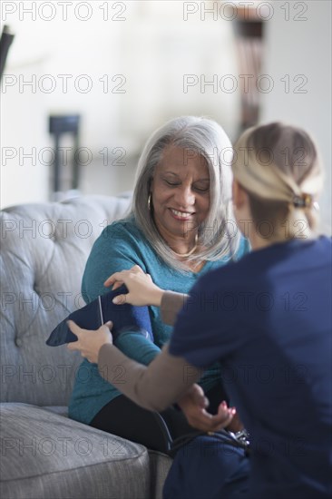 Nurse taking patient blood pressure in living room