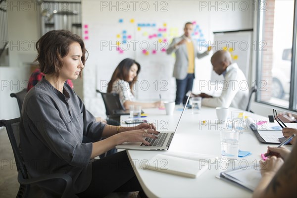 Businesswoman using laptop in office meeting