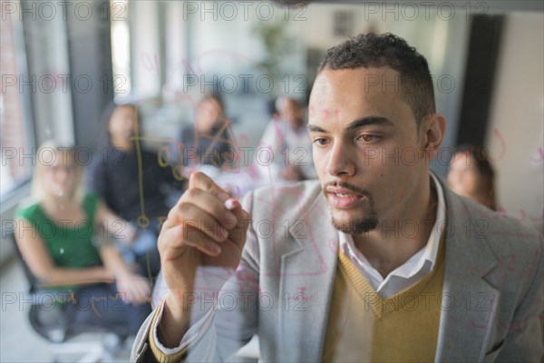 Businessman drawing graph on glass wall in office