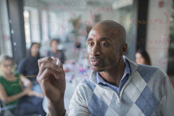 Businessman drawing graph on glass wall in office