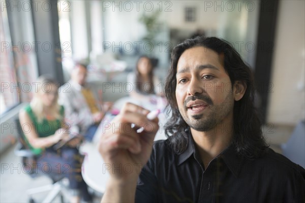 Businessman drawing graph on glass wall in office