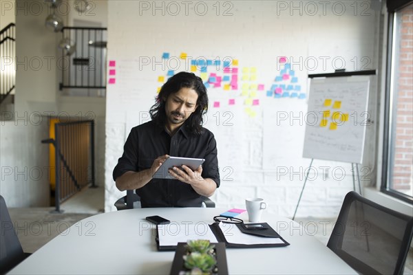 Mixed race businessman using digital tablet in office