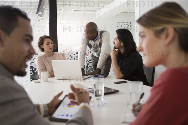 Business people using laptop and digital tablet in meeting