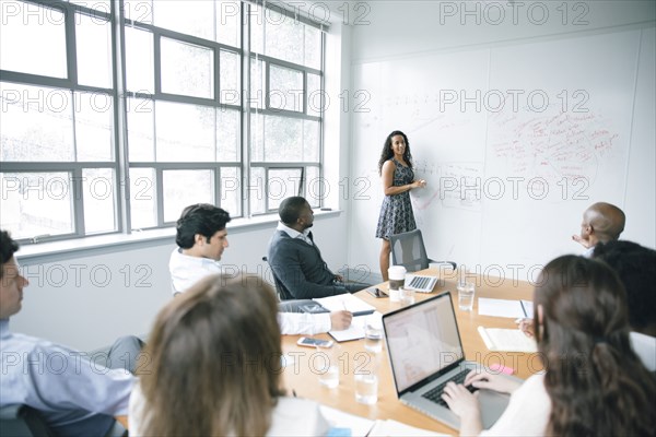 Businesswoman talking at whiteboard in meeting