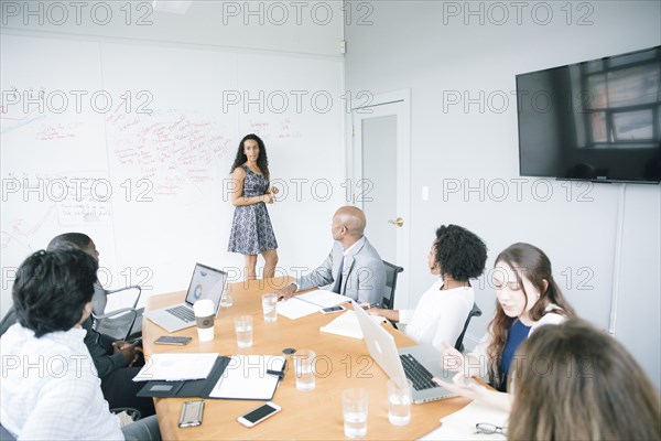 Businesswoman talking at whiteboard in meeting