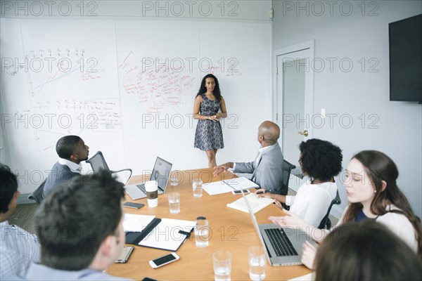 Businesswoman talking at whiteboard in meeting