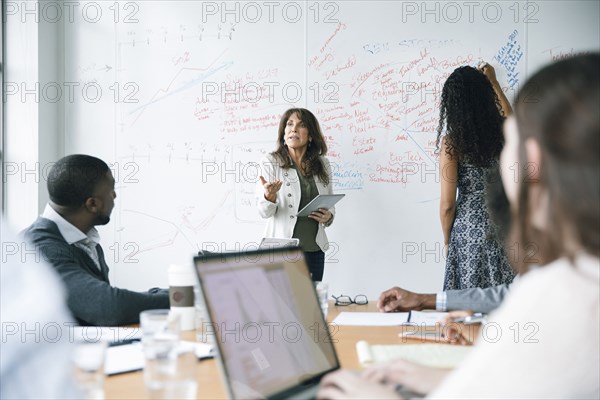 Businesswoman holding digital tablet near whiteboard in meeting