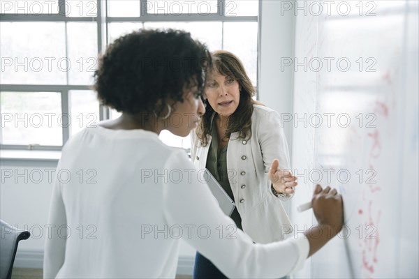 Businesswoman writing on whiteboard in meeting