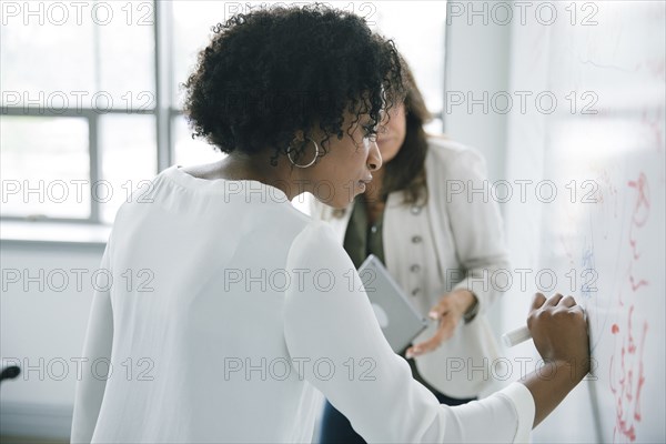 Businesswoman writing on whiteboard in meeting