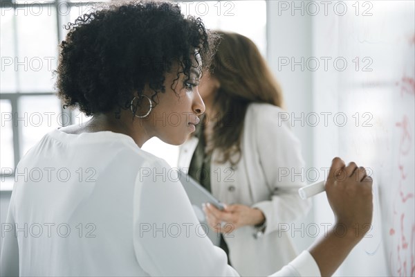 Businesswoman writing on whiteboard in meeting