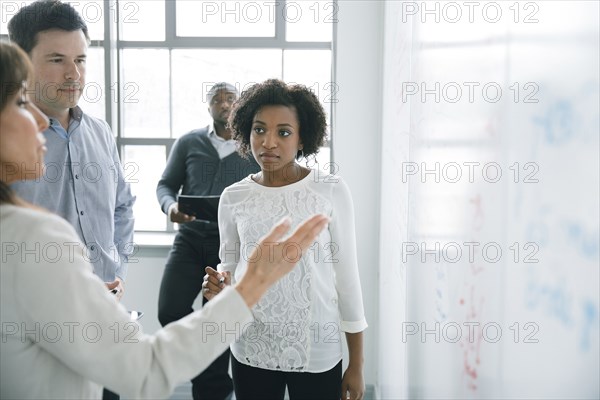 Business people talking near whiteboard in meeting