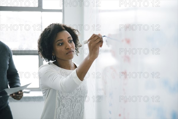 Businesswoman writing on whiteboard in meeting