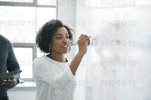 Businesswoman writing on whiteboard in meeting