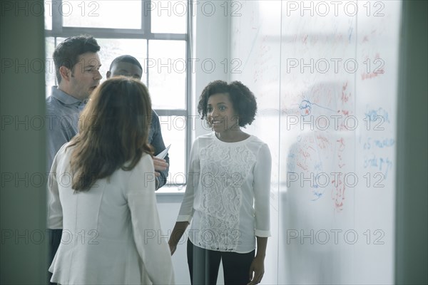 Business people talking near whiteboard in meeting