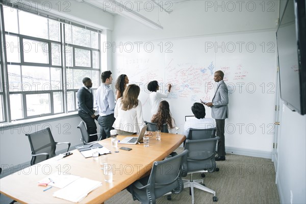 Businesswoman writing on whiteboard in meeting