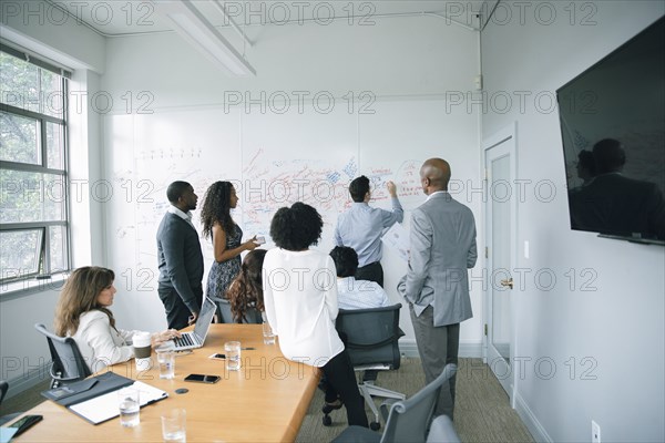 Businessman writing on whiteboard in meeting