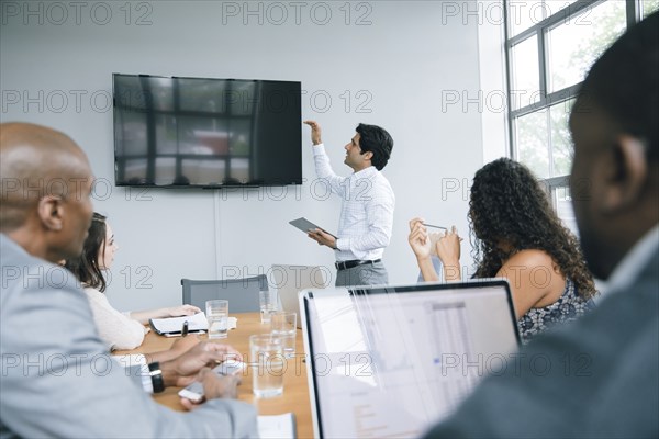 Businessman talking near visual screen in meeting