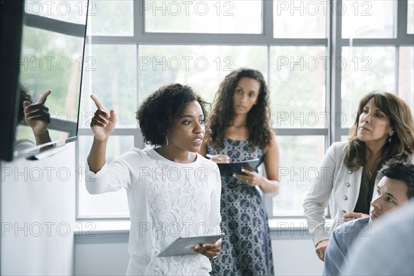 Businesswoman talking near visual screen in meeting