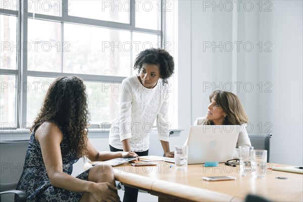 Businesswomen using laptop in meeting