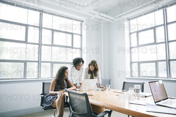 Businesswomen using laptop in meeting