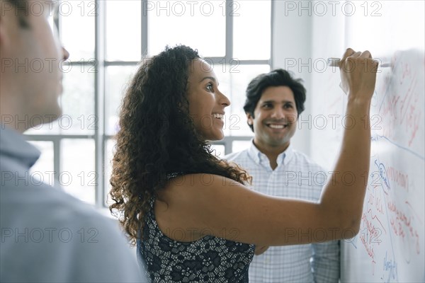 Businesswoman writing on whiteboard in meeting