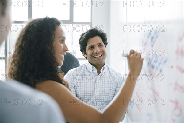 Businesswoman writing on whiteboard in meeting