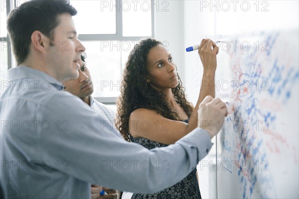 Business people writing on whiteboard in meeting