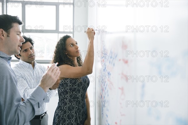 Businesswoman writing on whiteboard in meeting