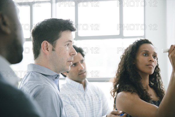 Businesswoman writing on whiteboard in meeting