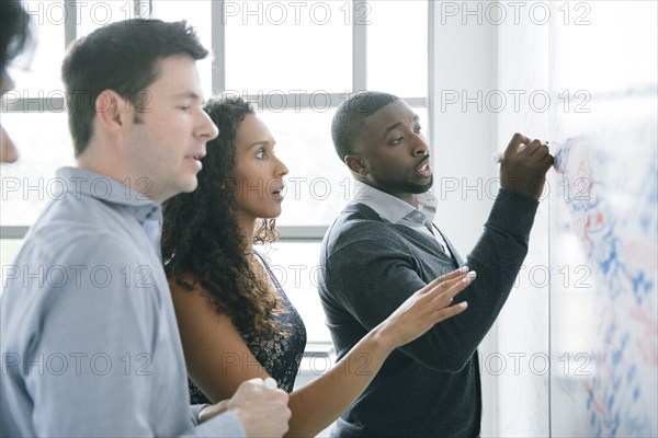 Businessman writing on whiteboard in meeting