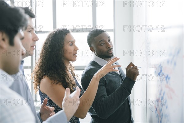 Businessman writing on whiteboard in meeting