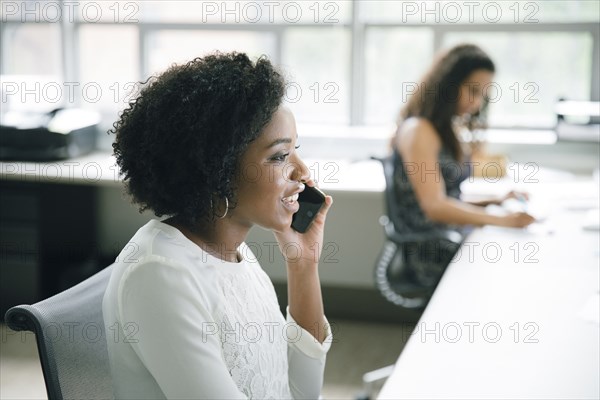 Businesswoman talking on cell phone in office