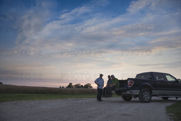 Caucasian men at pick-up truck at sunset