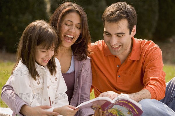 Hispanic family reading outdoors