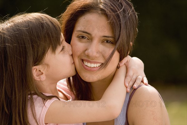 Hispanic girl kissing mother on cheek