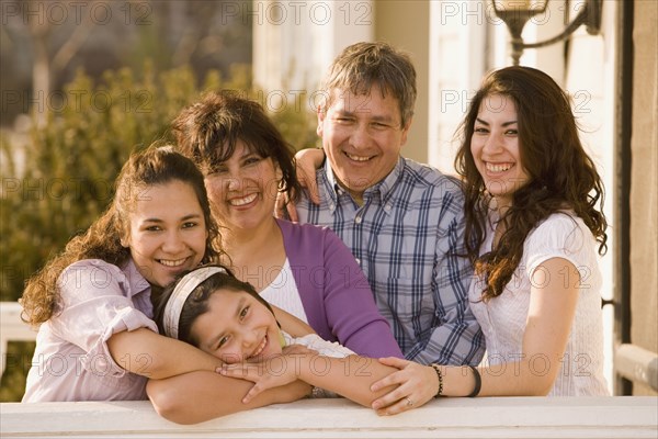 Hispanic family hugging on porch