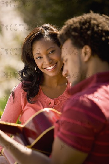 African American man playing guitar for girlfriend