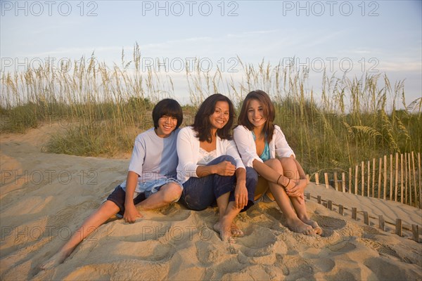 Asian woman and children sitting on beach