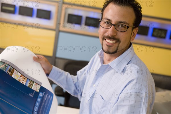 Hispanic male graphic designer holding printout