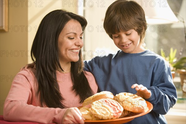 Hispanic mother and son holding plate of cookies