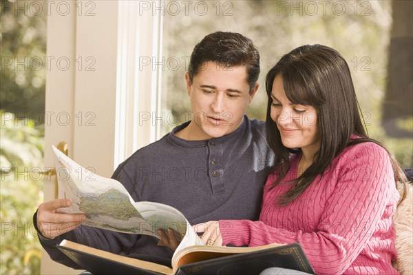 Hispanic couple looking at atlas