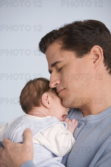 Hispanic father hugging baby