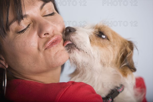 Dog licking Hispanic woman's face