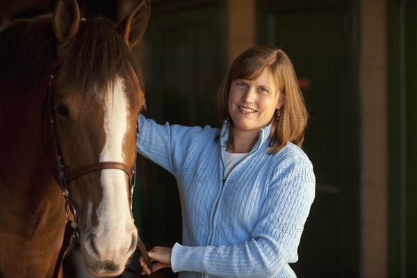 Caucasian woman standing with horse