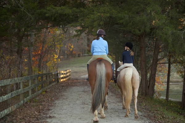 Caucasian girl and trainer riding horses